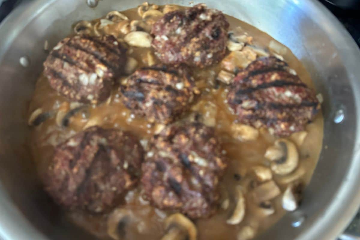 The burgers in the mushroom sauce in the pan.
