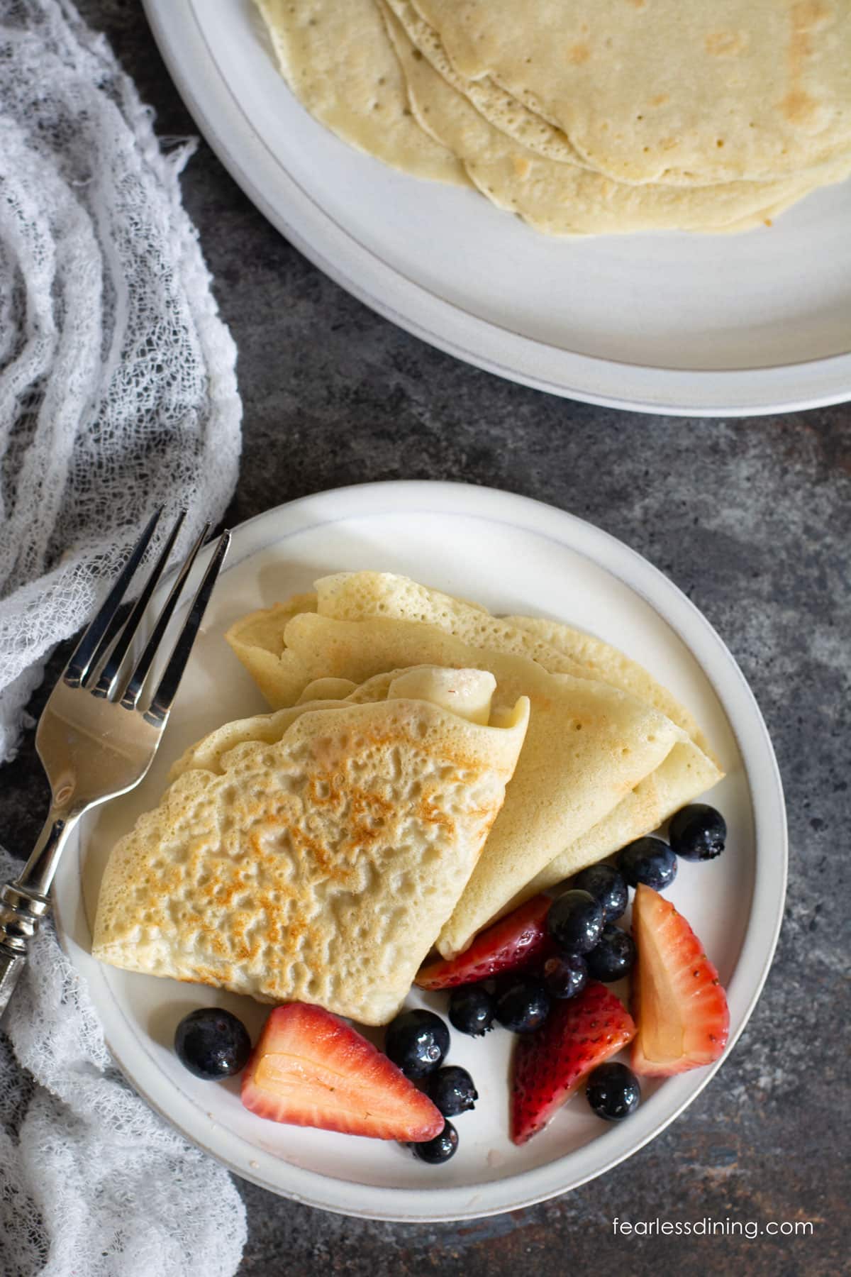 Gluten Free Folded crepes on a small white plate with fresh berries.