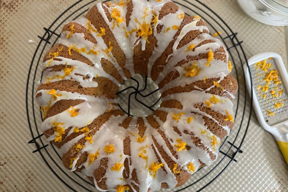 A photo of the cake with icing and orange zest on top.