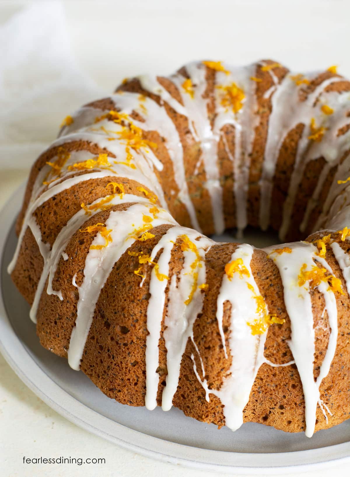 A photo of the orange bundt cake topped with icing and orange zest.