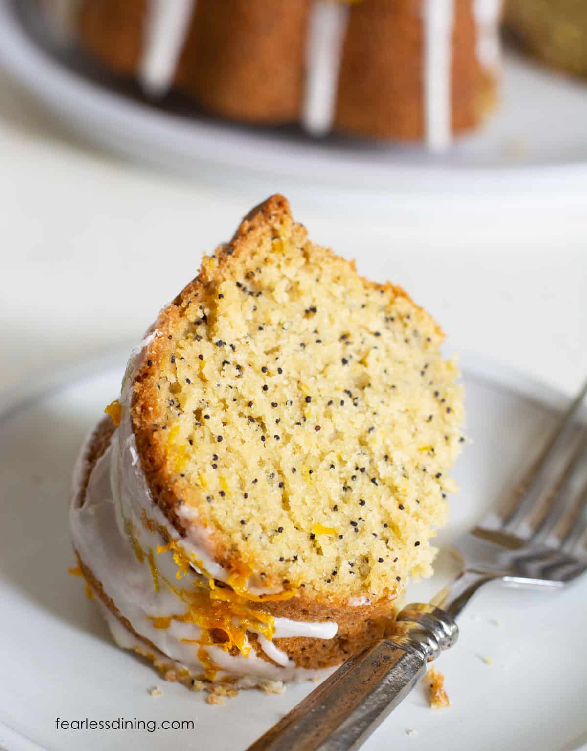 A slice of orange bundt cake on a small white plate.