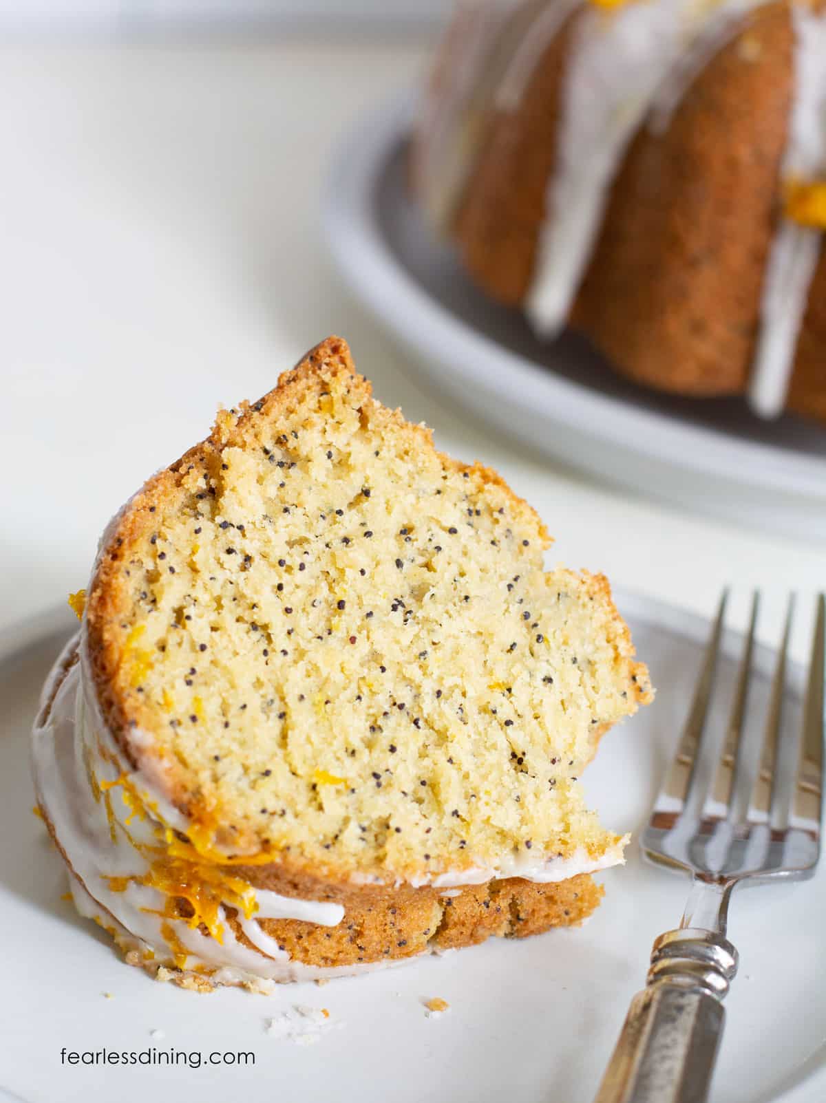 A slice of gluten free orange poppy seed cake on a plate.