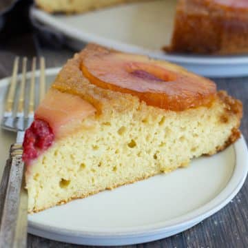 A close up of the pineapple upside down cake on a small white plate.