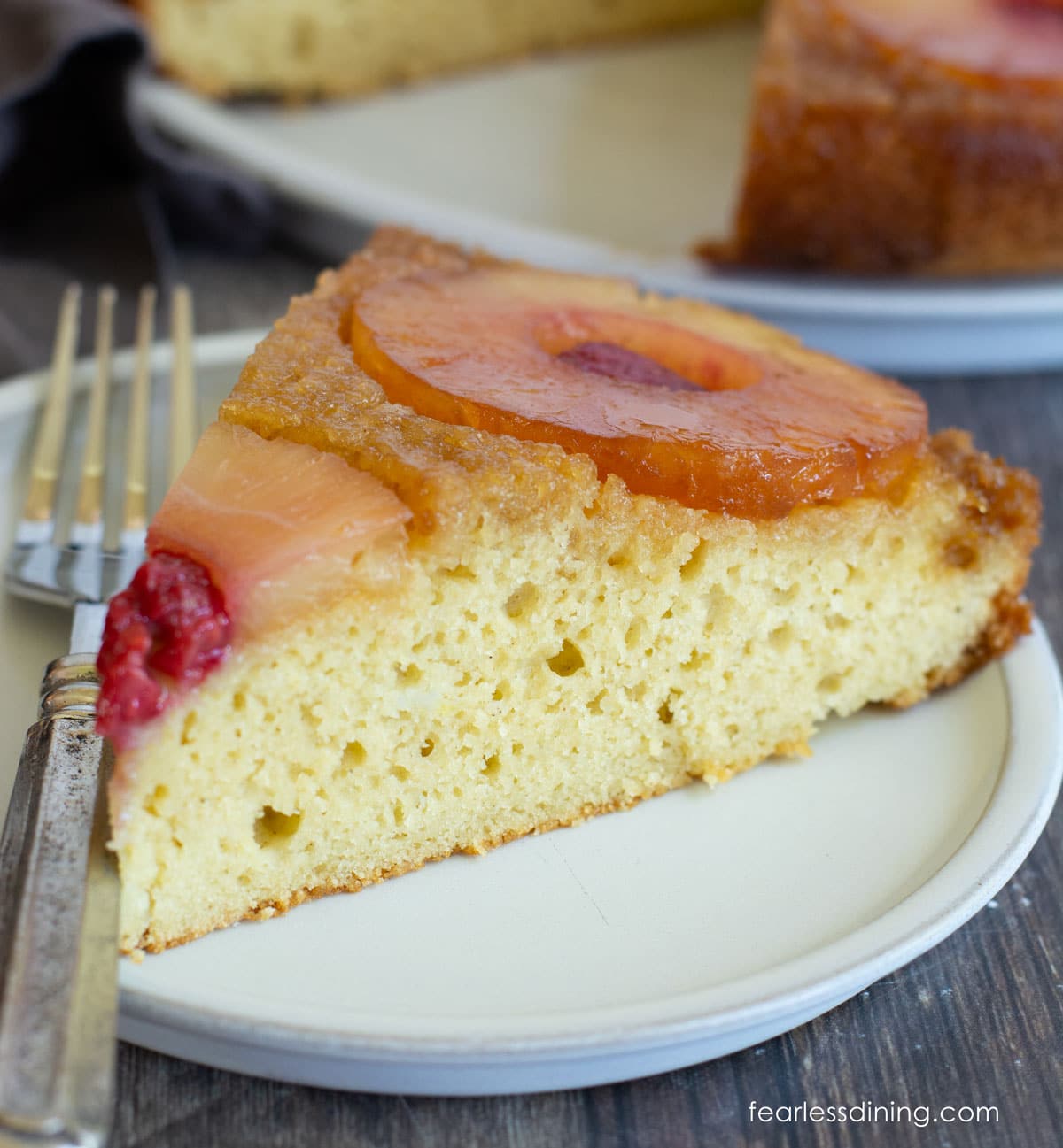 A close up of the pineapple upside down cake on a small white plate.