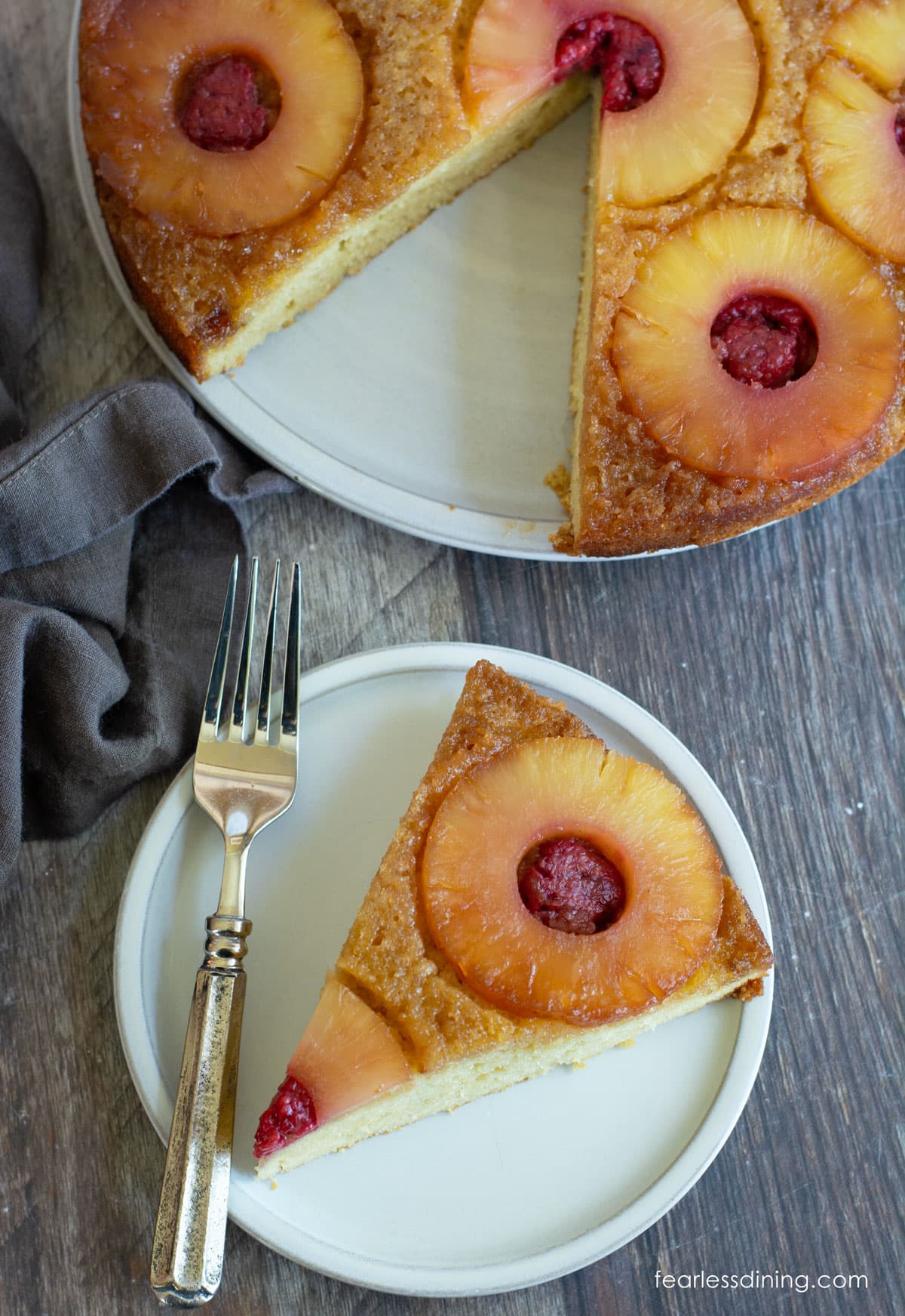 The top view of a slice of pineapple upside down cake next to the whole cake.