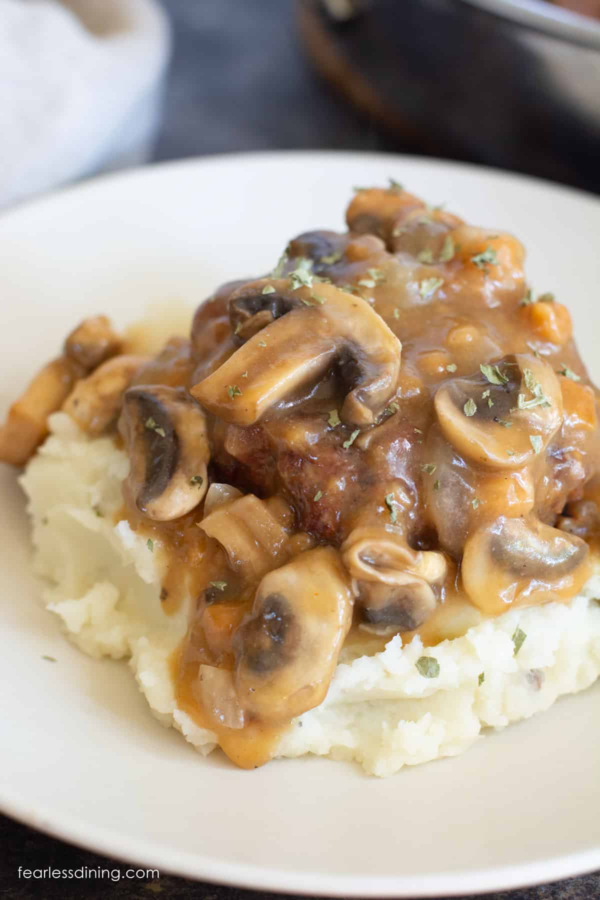 A serving of salisbury steak over mashed potatoes.