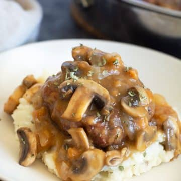 A salisbury steak topped with mushroom gravy on top of mashed potatoes.