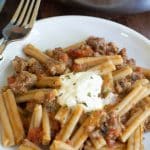 A plate full of gluten free cheeseburger pasta. A dollop of sour cream is on top as a garnish.