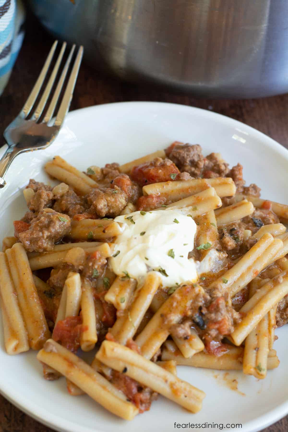 A plate full of gluten free cheeseburger pasta. A dollop of sour cream is on top as a garnish.