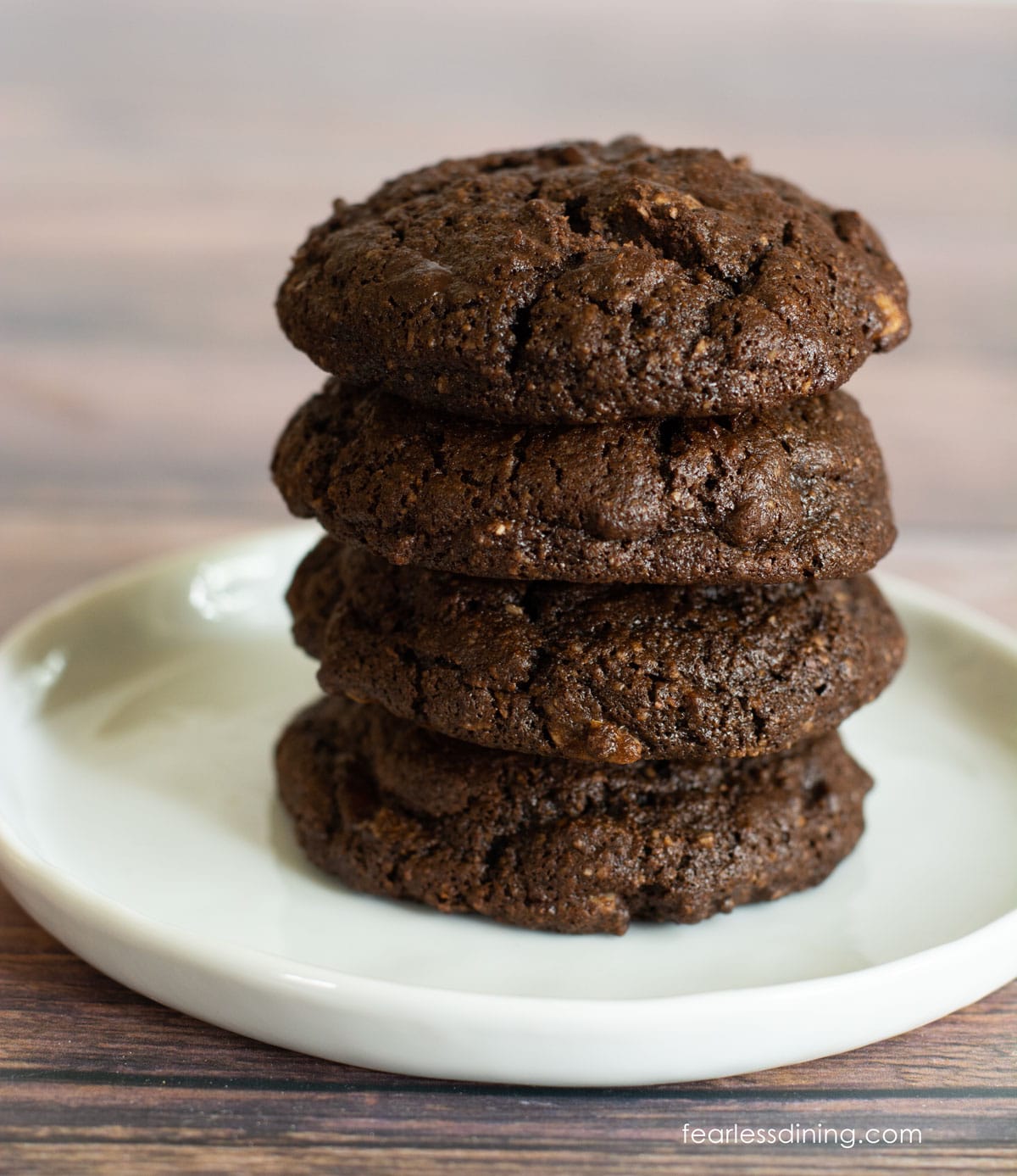 A stack of four double chocolate gluten free cake mix cookies on a small white plate.