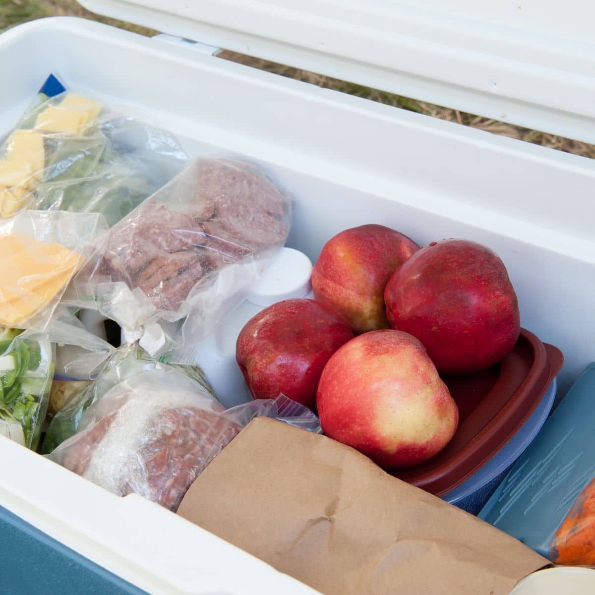 A big cooler packed with food and containers for camping.