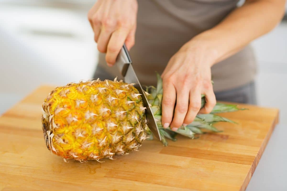 Cutting the top off of a pineapple.
