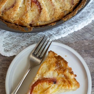 The top view of a slice of peach kuchen next to the whole cake.