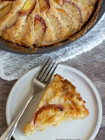 The top view of a slice of peach kuchen next to the whole cake.