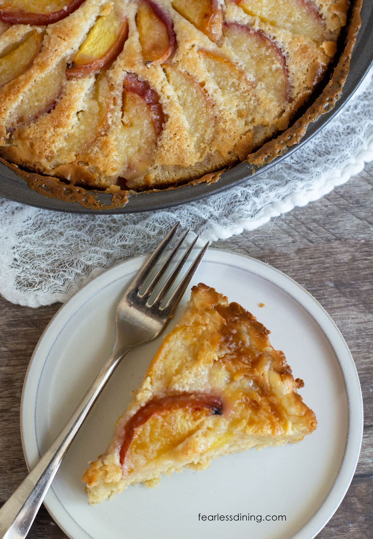The top view of a slice of peach kuchen next to the whole cake.