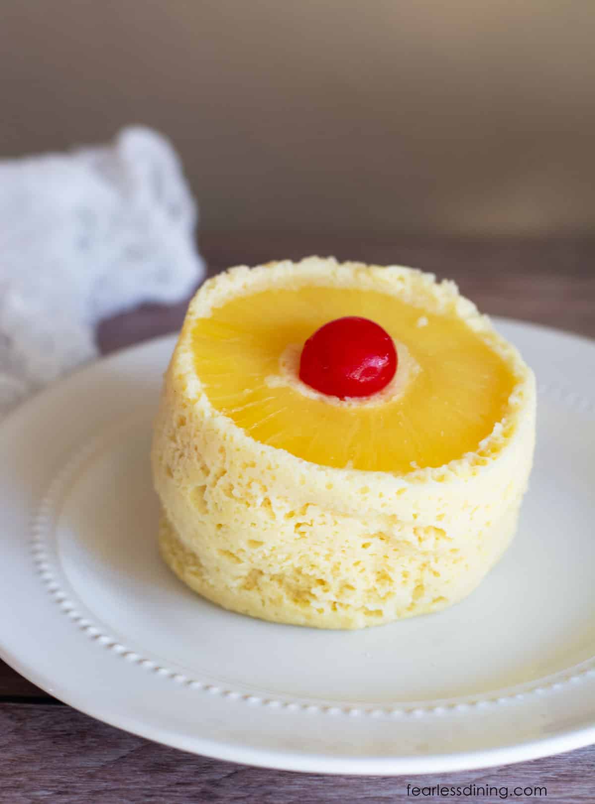 A gluten free pineapple upside down mug cake on a white plate.