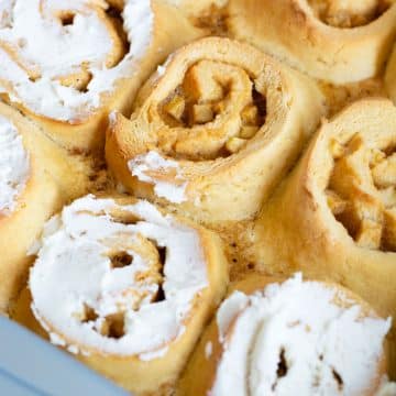 A baking pan filled with apple cinnamon rolls. Three are frosted.