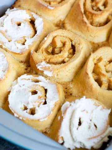 A baking pan filled with apple cinnamon rolls. Three are frosted.