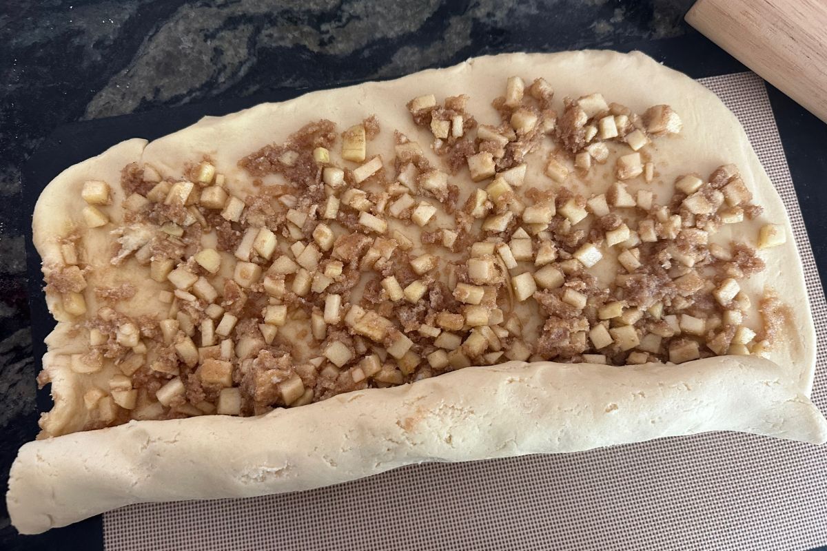 Rolling the dough over the apple sugar mixture.