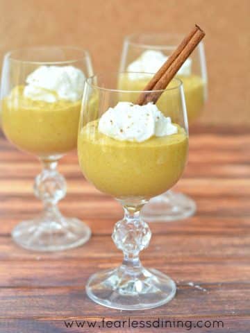 Three wine glasses filled with kabocha mousse and whipped cream.