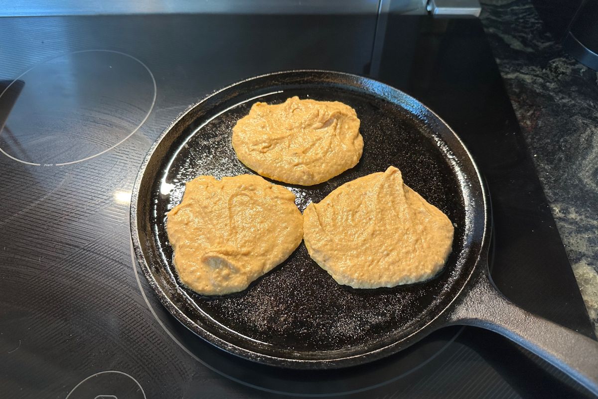 Pancake batter on a cast iron skillet.