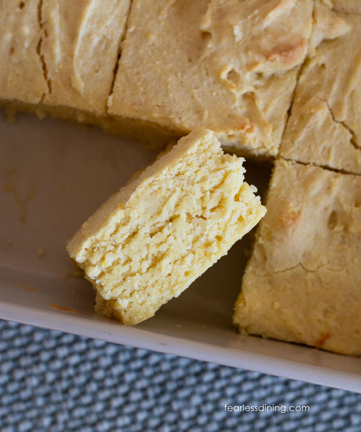 A cut piece of cornbread on its side so you can see the inside texture of the cornbread.