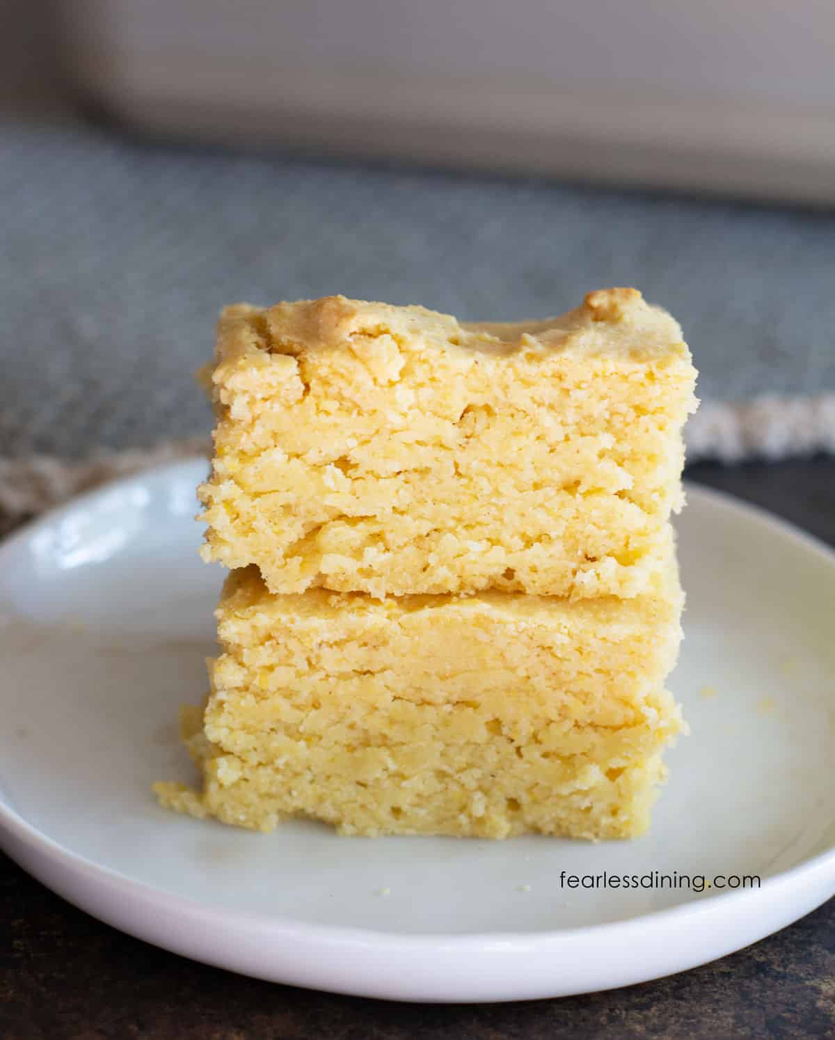 A stack of two slices of cornbread on a small white plate.