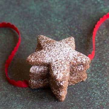Three star shaped Swiss Brunsli Cookies with red ribbon.