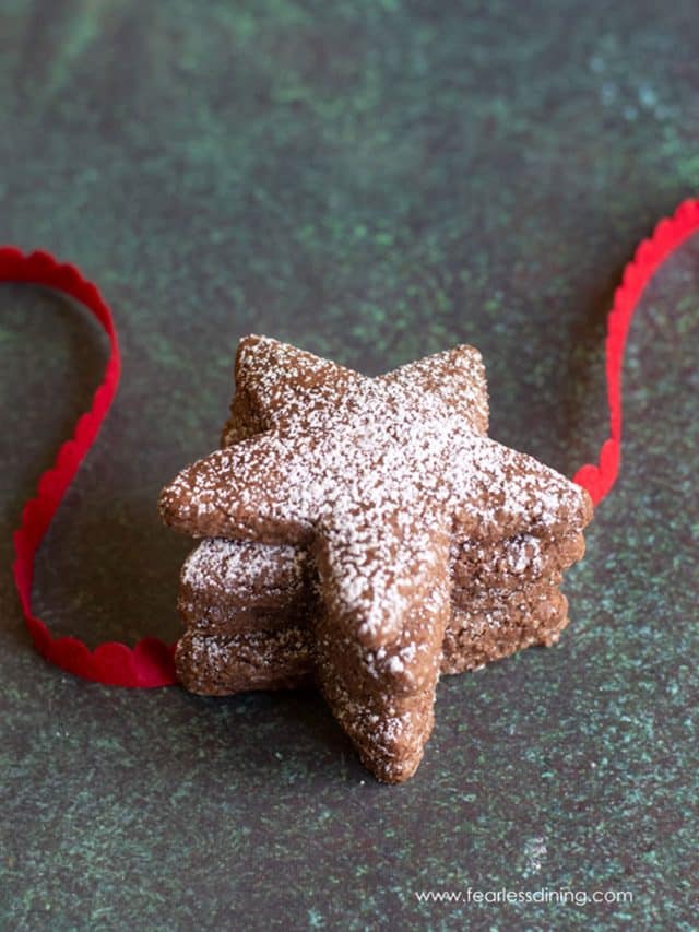 Three star shaped Swiss Brunsli Cookies with red ribbon.