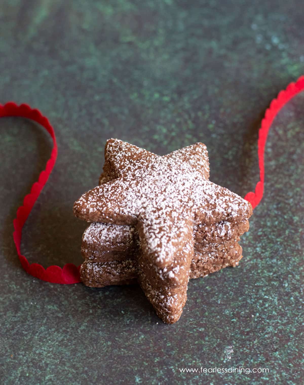 Three star shaped Swiss Brunsli Cookies with red ribbon.
