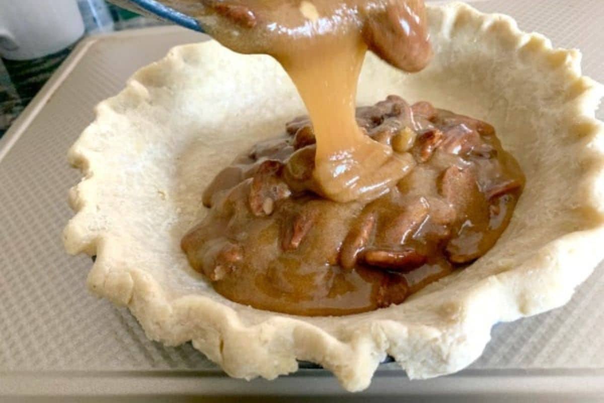 Pouring the pecan sugar mixture into a pie crust.