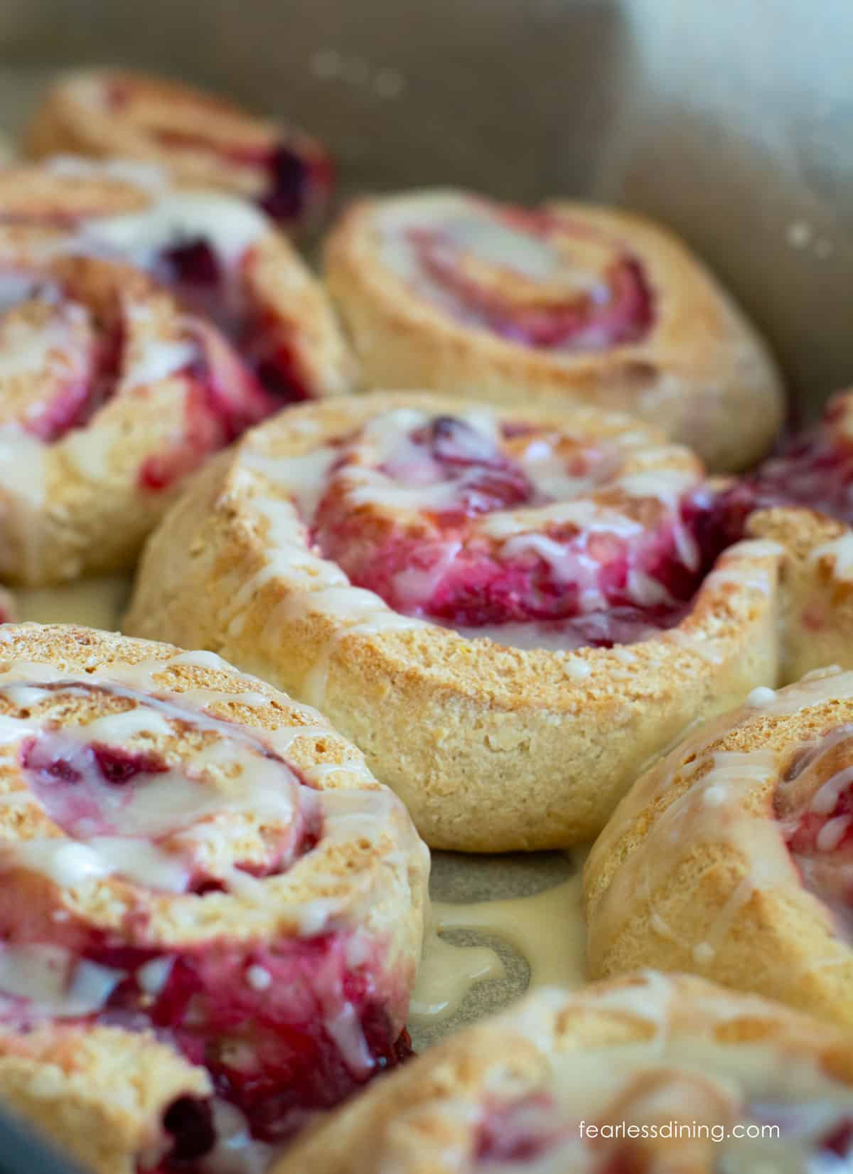A close up of the baked gluten free cranberry rolls topped with glaze.
