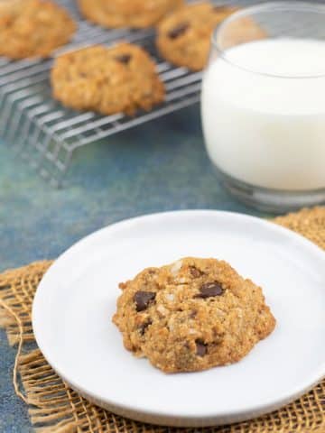 A grain-free paleo chocolate chip cookie on a plate next to a glass of milk.