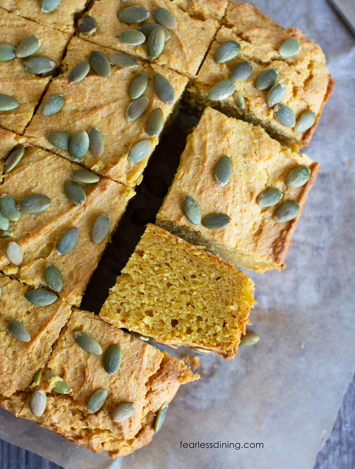 Baked, sliced gluten free pumpkin cornbread. One piece is on its side so you can see the inside.