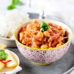 A bowl full of chicken and chickpea stew on a tray.