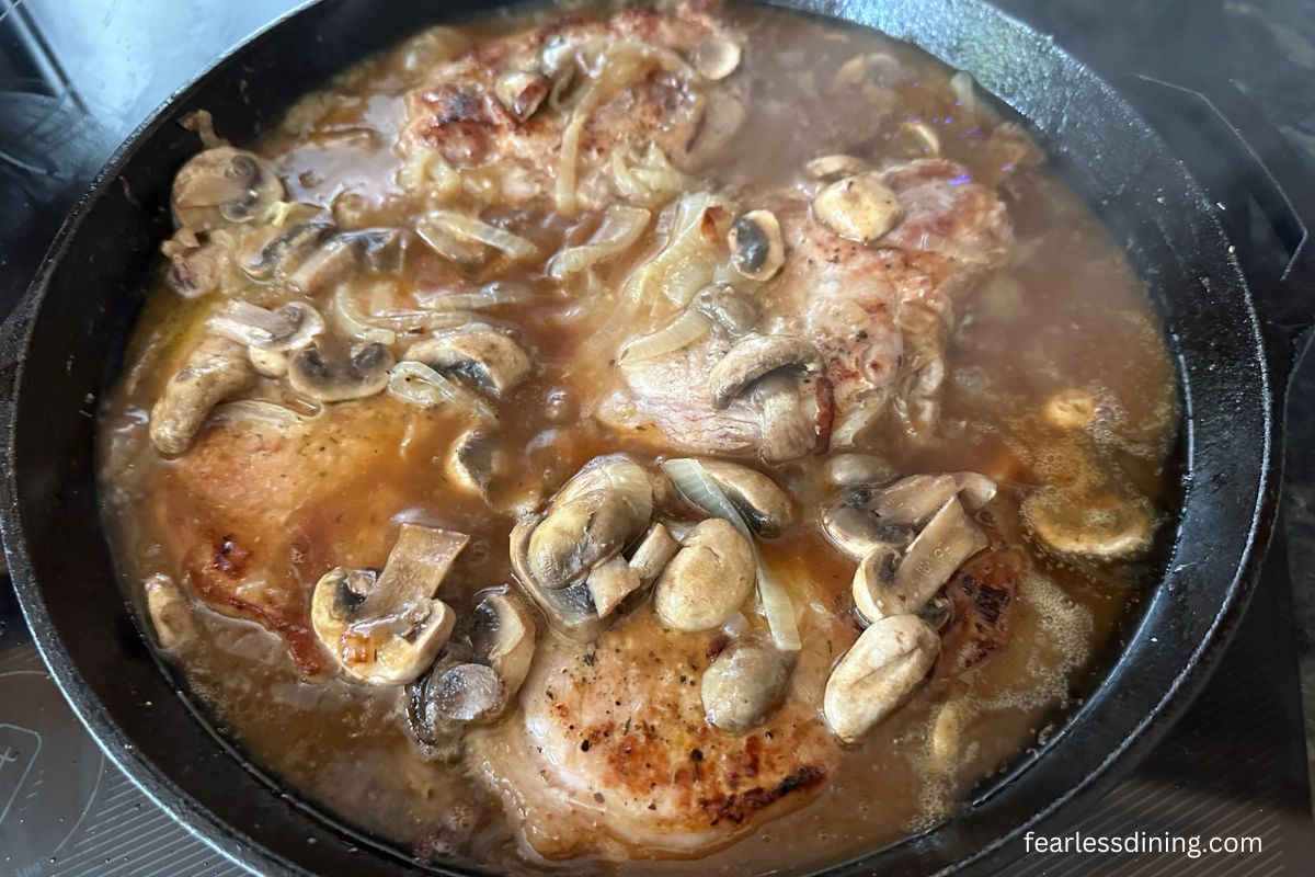 The pork chops simmering in the sauce.