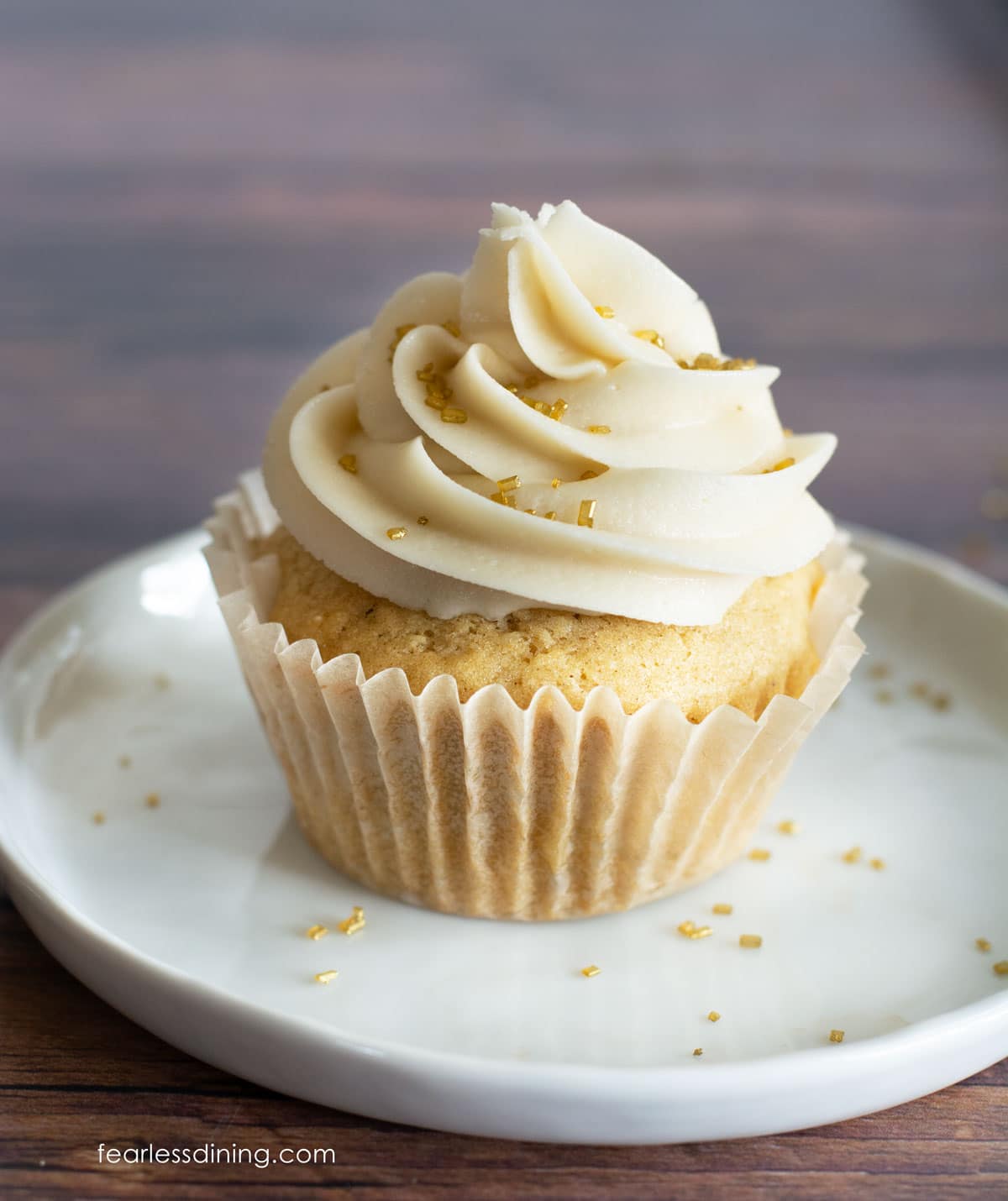 A single frosted cupcake on a small white plate.