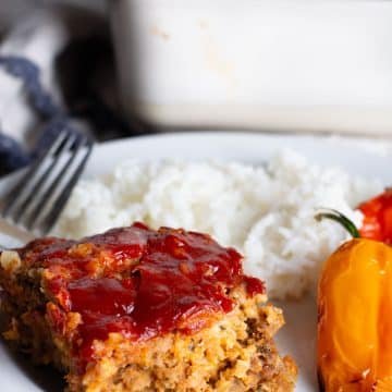 A slice of gluten free meatloaf with oats with rice and roasted peppers.