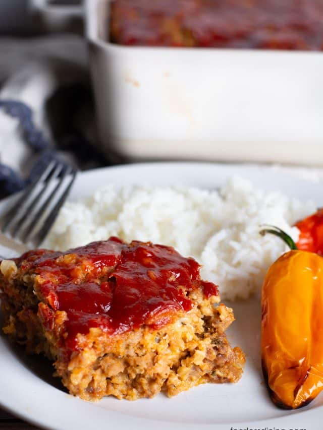 A slice of gluten free meatloaf with oats with rice and roasted peppers.