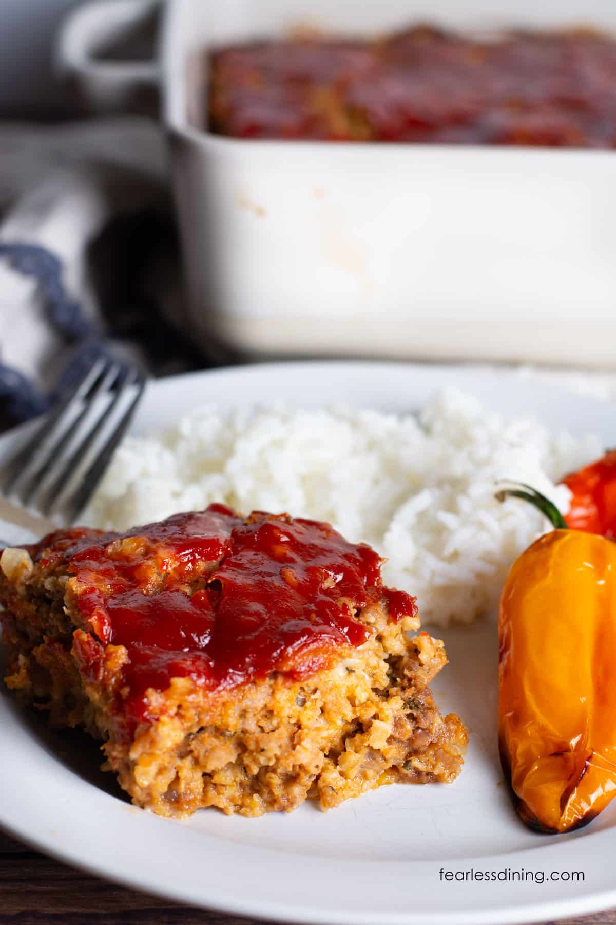 A slice of gluten free meatloaf with oats with rice and roasted peppers.