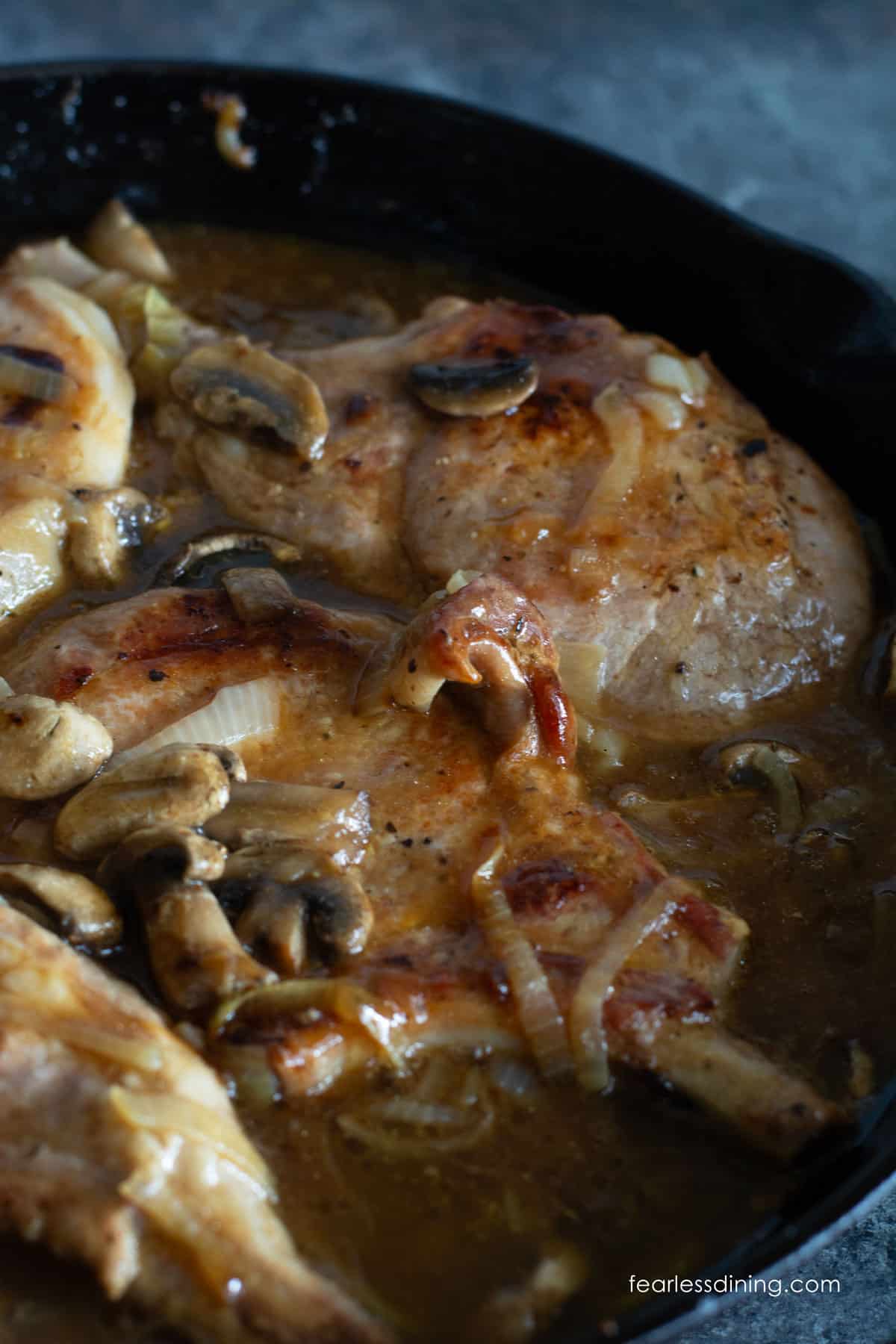 A close up of the cooked pork chops in a cast iron skillet.