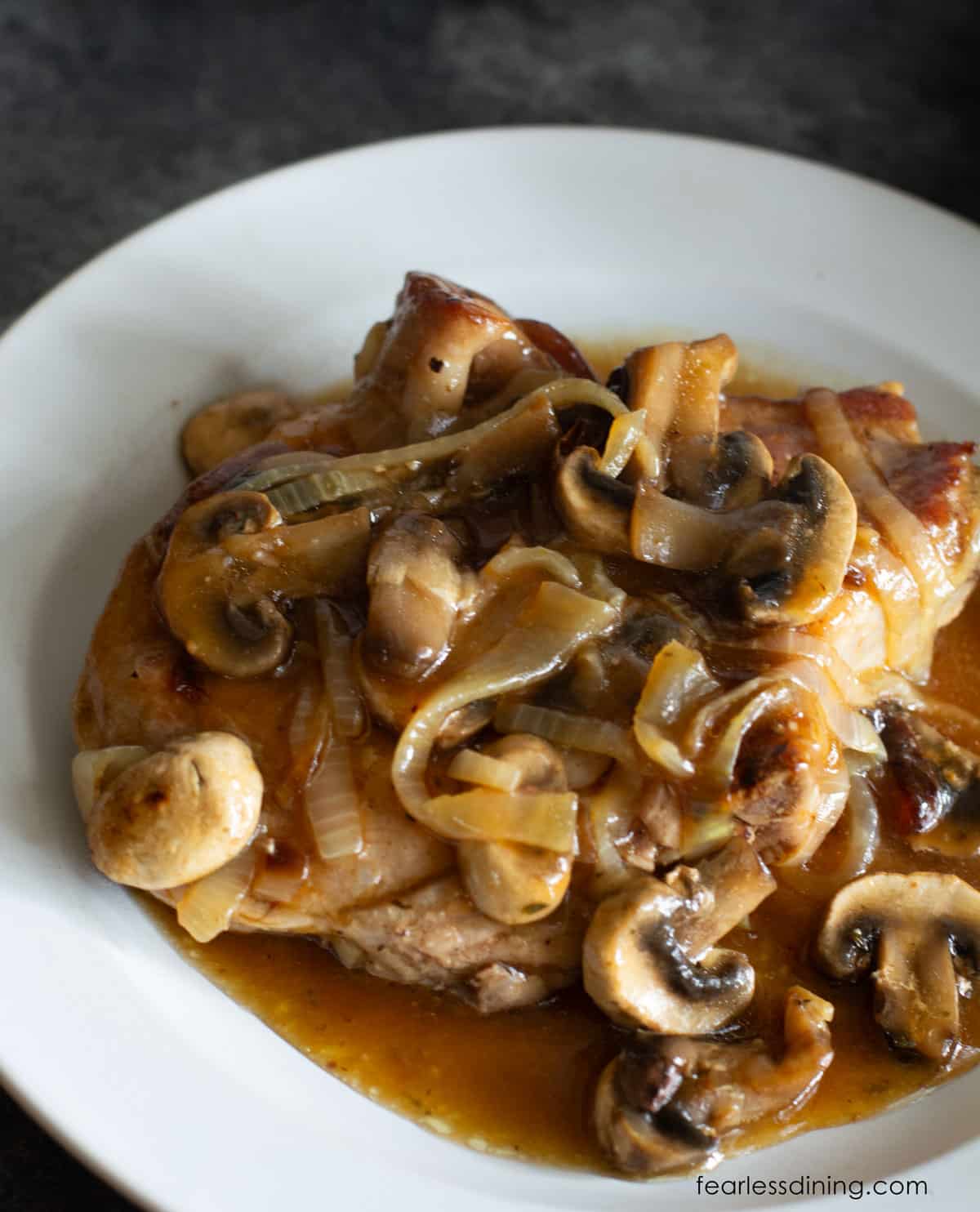 The top view of a pork chop topped with caramelized onions and mushrooms.
