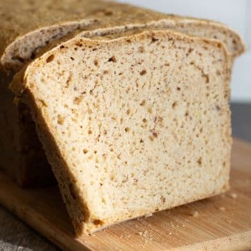 A sliced loaf of gluten free rice free bread on a wooden cutting board.