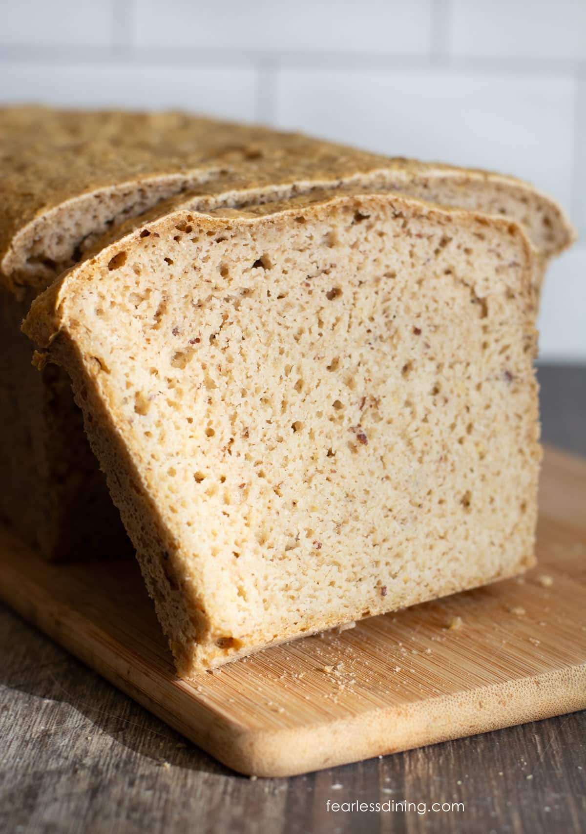 A sliced loaf of gluten free rice free bread on a wooden cutting board.