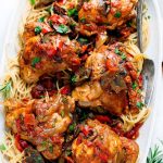 A serving platter full of slow cooker chicken cacciatore over pasta.