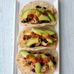 Three slow cooker chicken soft tacos on a rectangular plate.