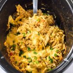 Cooked slow cooker queso chicken in the slow cooker.