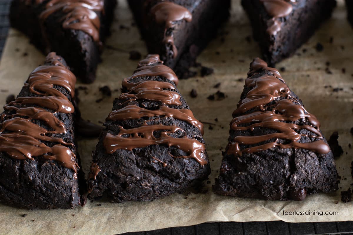 The gluten free chocolate scones on a baking sheet. They are topped with a melted chocolate drizzle.