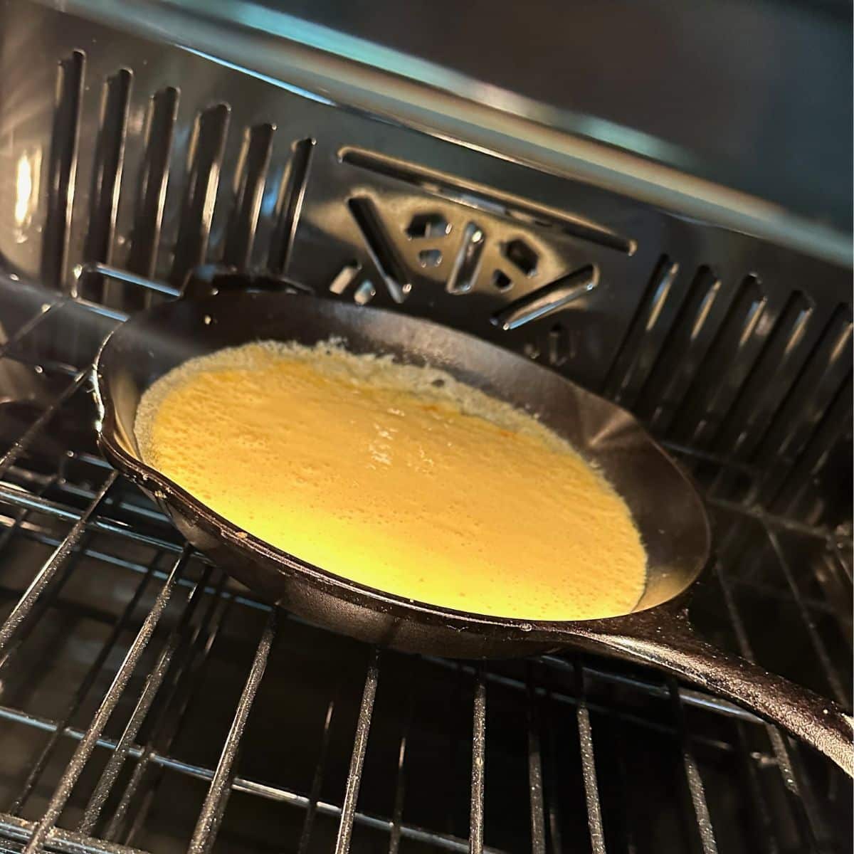 The pan with pancake batter in the oven.