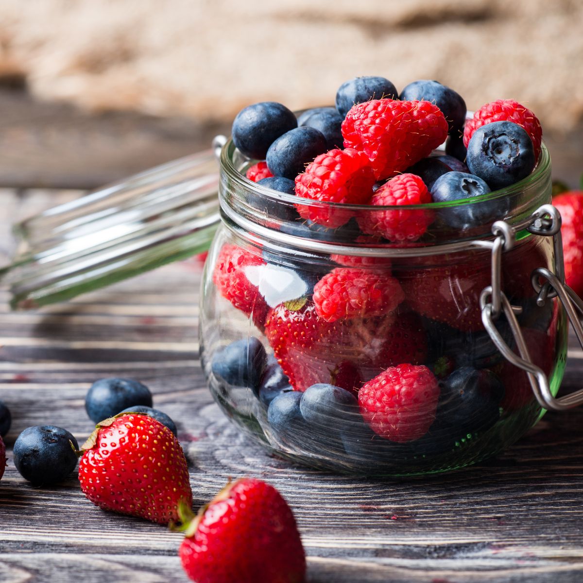 Fresh strawberries, raspberries, and blueberries in a jar.